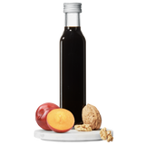 A bottle of Plum Walnut Vinegar with a small plate containing sliced plum and walnut pieces in front.