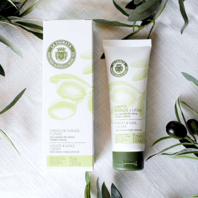 A tube of hand cream with EVOO next to its packaging box, both featuring olive branch graphics.