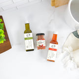 Bottles of olive oil and spices on a kitchen counter with a mug and towel.