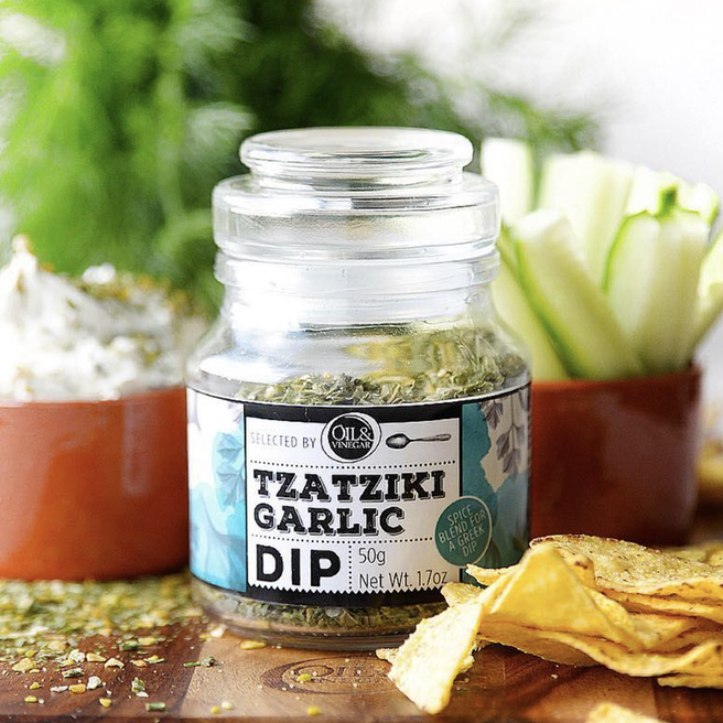 A jar of Tzatziki Garlic Dip showing the product label which includes herbs and indicates it is a garlic dip.