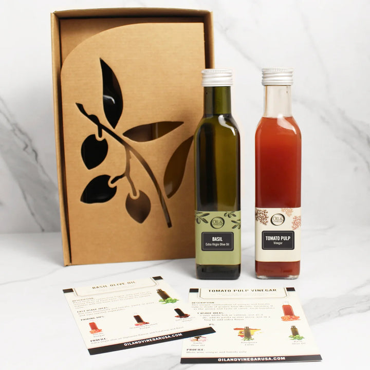 Two bottles of tomato vinegar and garlic olive oil with tomatoes and garlic